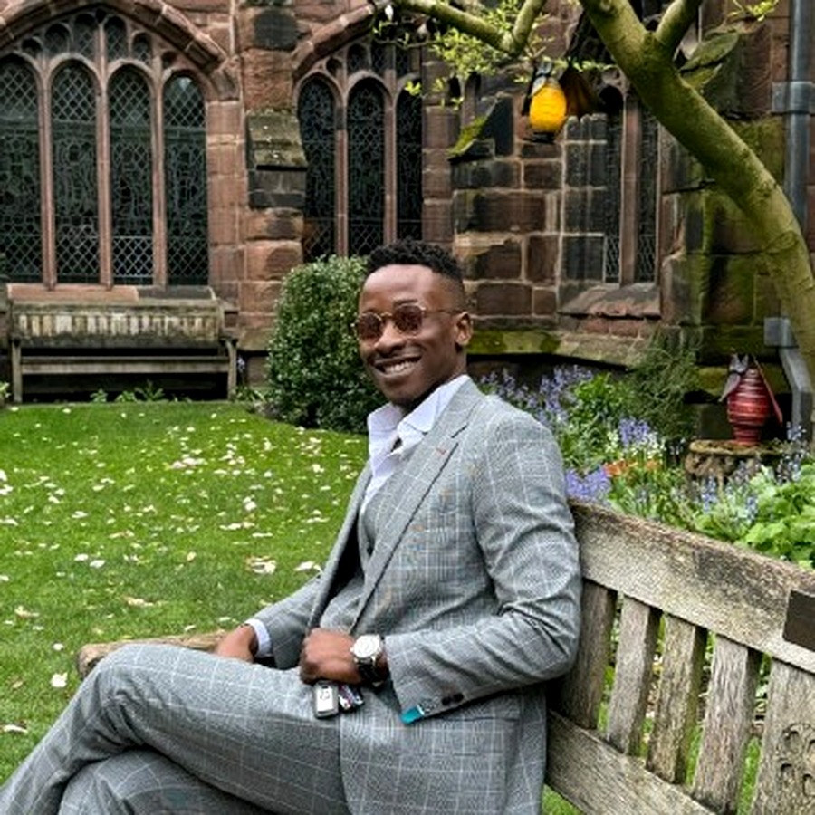 Ebube Glory Ogbonda smiling in a grey suit in a university garden